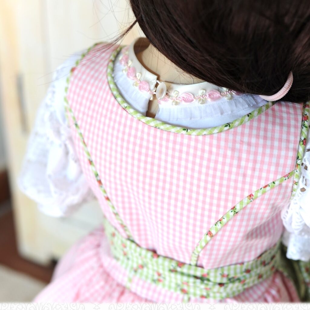 Detailansicht des Mieders vom Kinderdirndl Resli mit grün-weißem Karomuster und Paspelierung. Das Schnittmuster Kinderdirndl Gr. 80-140 zeigt hier die saubere Verarbeitung der Wiener Nähte und des Ausschnitts.