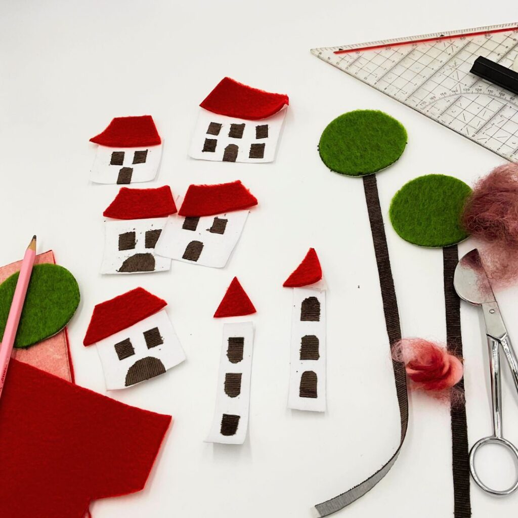 Einzelteile für Haus-Applikationen aus Stoff – ausgeschnittene Häuser, Dächer, Bäume und Fenster zur Vorbereitung der Applikation